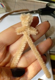 a person holding a tiny stuffed animal in their left hand and scissors on the right