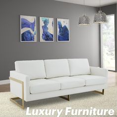 a white couch sitting next to two paintings on the wall