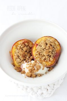 two peaches with crumbled topping in a white bowl