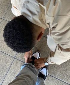 a man standing on top of a tile floor next to a person with an afro