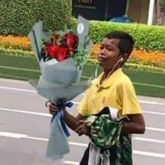 a young man holding a bunch of flowers and listening to headphones on his ear