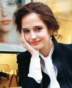 a woman sitting at a table with her hand on her chin and looking off to the side