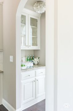 a bathroom with white cabinetry and marble counter tops, along with hardwood floors in front of it