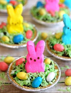 some little bunnies are sitting in the grass with easter eggs around them and peeps