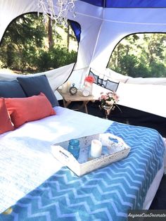 a blue and white bed in a tent next to a table with food on it