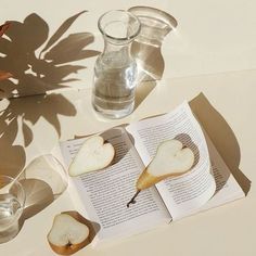 an open book sitting on top of a table next to two glasses filled with water