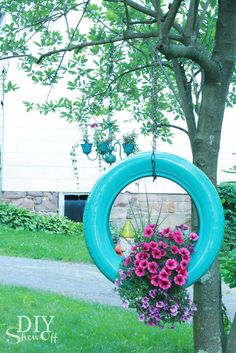 a blue tire hanging from a tree filled with flowers