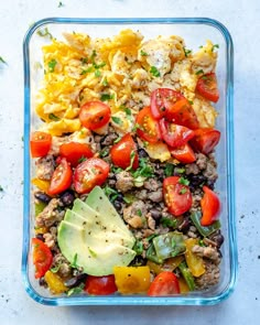 a glass dish filled with rice and vegetables next to an avocado on the side