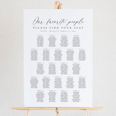 the seating chart for an event is displayed on a wooden easel with a white background