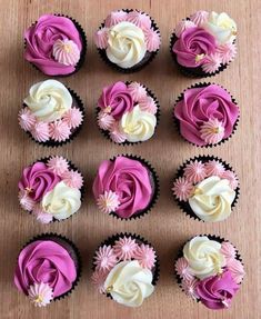 several cupcakes with pink and white frosting on top of a wooden table