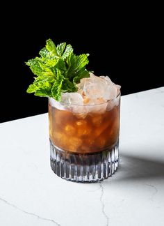 a glass filled with ice and mint on top of a table