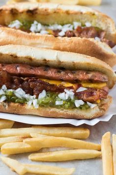 two hot dogs with toppings and french fries