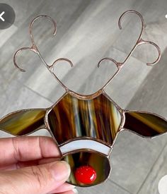 a hand holding a stained glass reindeer decoration