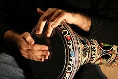 a man is holding a large black drum in his hand and touching it with both hands