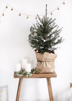 a small christmas tree sitting on top of a wooden table next to two white candles