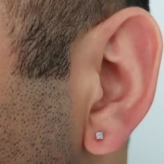 a close up of a man's ear with a single diamond in the middle