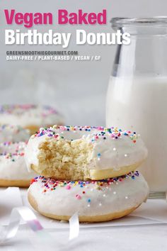 two white frosted donuts with sprinkles next to a glass of milk