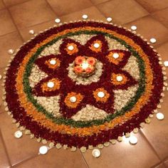 a flower arrangement on the floor with candles around it for diwaling or decorating