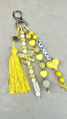 a key chain with beads and tassels attached to it on a gray surface