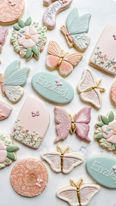 many decorated cookies on a table with name tags and butterfly decorations in pastel colors