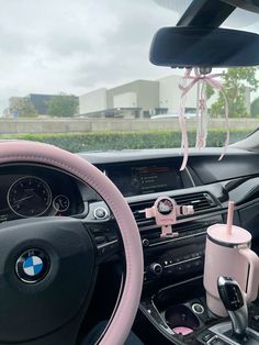 the interior of a car with pink steering wheel and cup holder attached to the dashboard