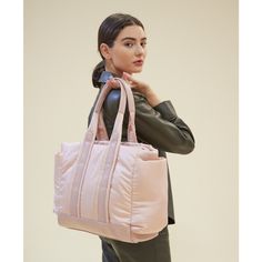 a woman is carrying a pink bag on her shoulder and looking off to the side