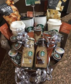 starbucks coffee drinks and snacks in a basket on a table with some signs above it