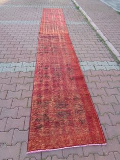 a long red rug sitting on top of a brick walkway