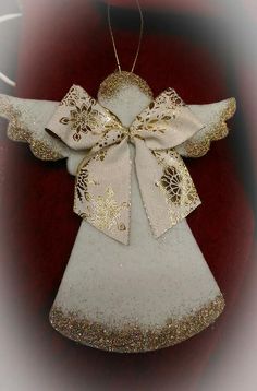 an angel ornament hanging on a red tablecloth with gold glitters and sequins