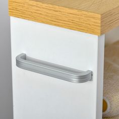 a close up of a drawer on a white cabinet with wood top and bottom panel