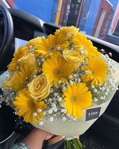 a bouquet of yellow daisies and baby's breath in the driver's seat of a car