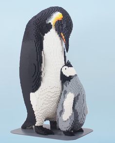 two penguins are standing next to each other in front of a light blue background and one penguin has its head on another penguin's back