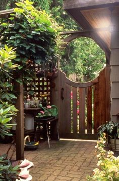 an outdoor patio area with potted plants and a wooden arbor in the center, surrounded by greenery