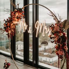 the wedding arch is decorated with flowers and greenery, along with mr and mrs letters