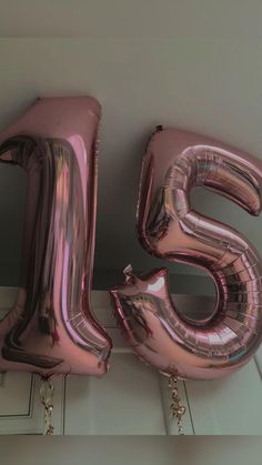 the number twenty five is made out of shiny pink foil and hangs from the ceiling