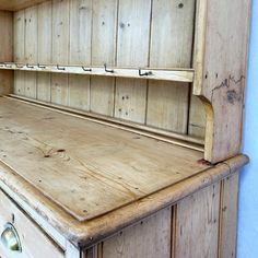 an old fashioned wooden desk with drawers and cupboards on the top, in front of a blue wall