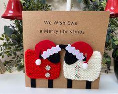 two knitted sheeps with santa hats on their heads are standing in front of a christmas card