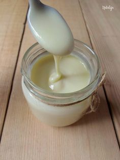 a spoon is pouring cream into a jar