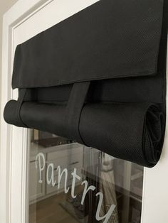 a black curtain hanging on the side of a white door with words pantry written in it