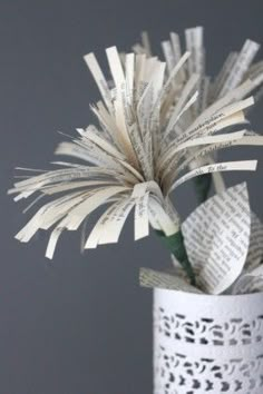 a white vase filled with lots of paper and flowers on top of a wooden table