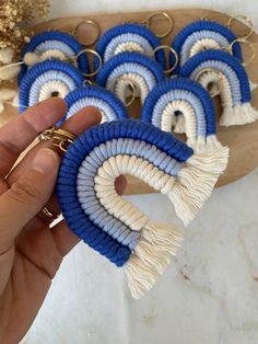 a person holding some kind of blue and white keychain with tassels on it