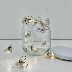 a glass jar with string lights in it sitting next to a white plate on the table