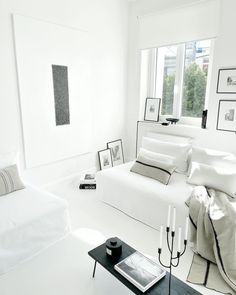 a white room with black and white decor on the walls, windows, and bed