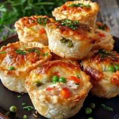 several small pastries on a black plate with green peas and parsley around them