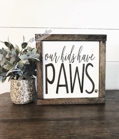 a potted plant sitting on top of a wooden table next to a sign that says our kids have paws