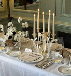 a table set with candles, plates and silverware for a formal dinner or party