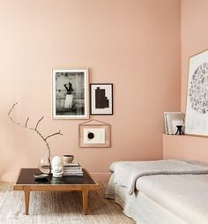 a living room with pink walls and pictures on the wall, coffee table and bed