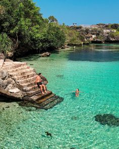 two people are swimming in clear blue water