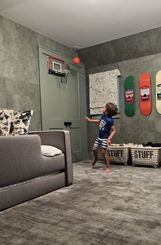 a young boy is playing basketball in his living room with skateboards on the wall