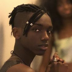 a young man with dreadlocks is looking at the camera while another looks on